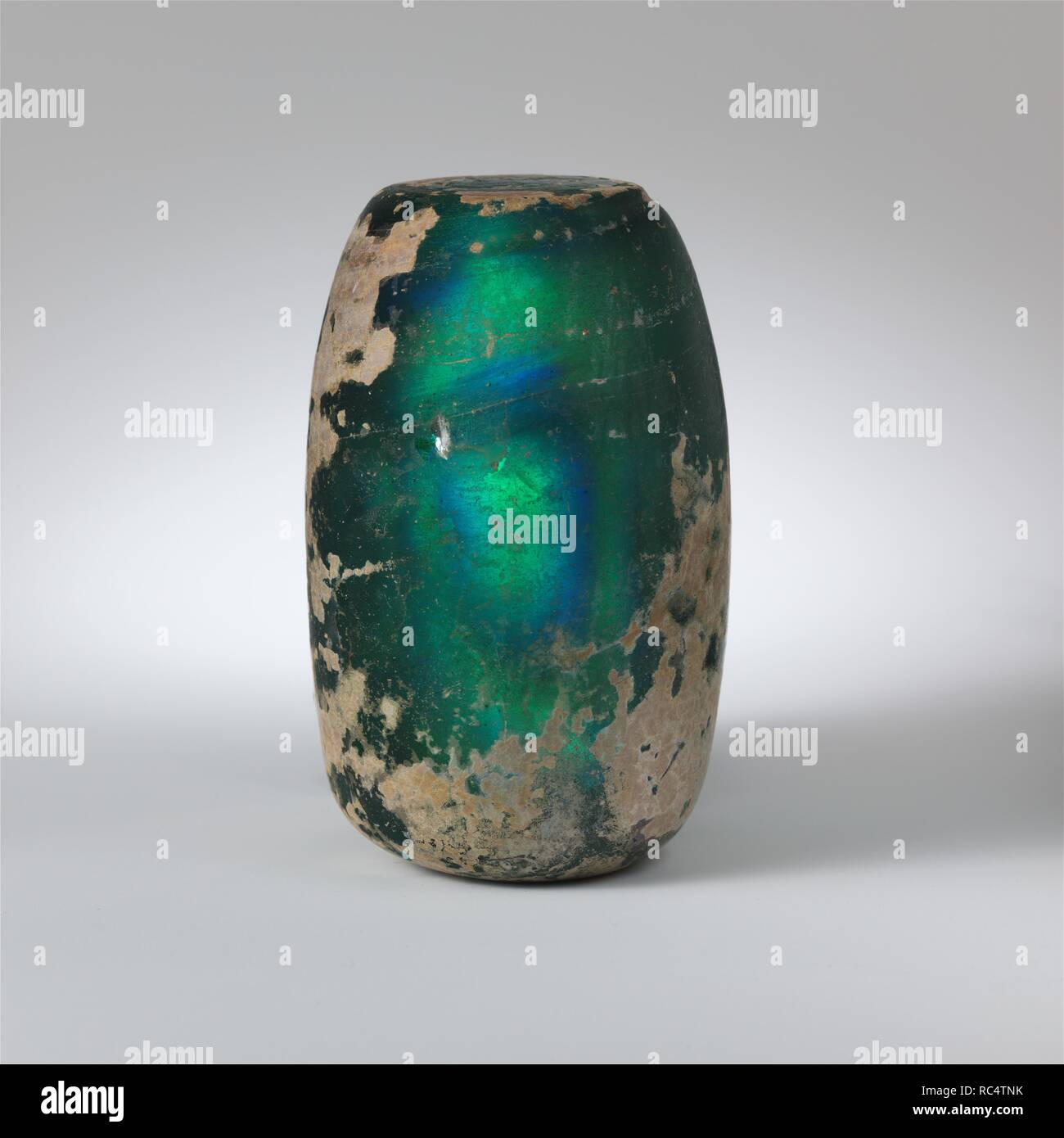 Glass weight. Culture: Roman (?). Dimensions: Height: 4 1/16 in., (10.3 cm)  Weight: 1.9 lb. (861.8g). Date: 1st century A.D. or later.  Translucent turquoise blue.  Solid cylindrical shape; flat top; convex side; bottom slightly concave with projecting pontil scar at center.  Intact, but one small surface chip and crack in side; few bubbles; dulling, creamy weathering, and brilliant iridescence.  This unusual object may be seen as a glass weight. The brilliant turquoise color resembles that of some early Roman glass but it probably belongs to the early  Islamic period. Museum: Metropolitan Mu Stock Photo