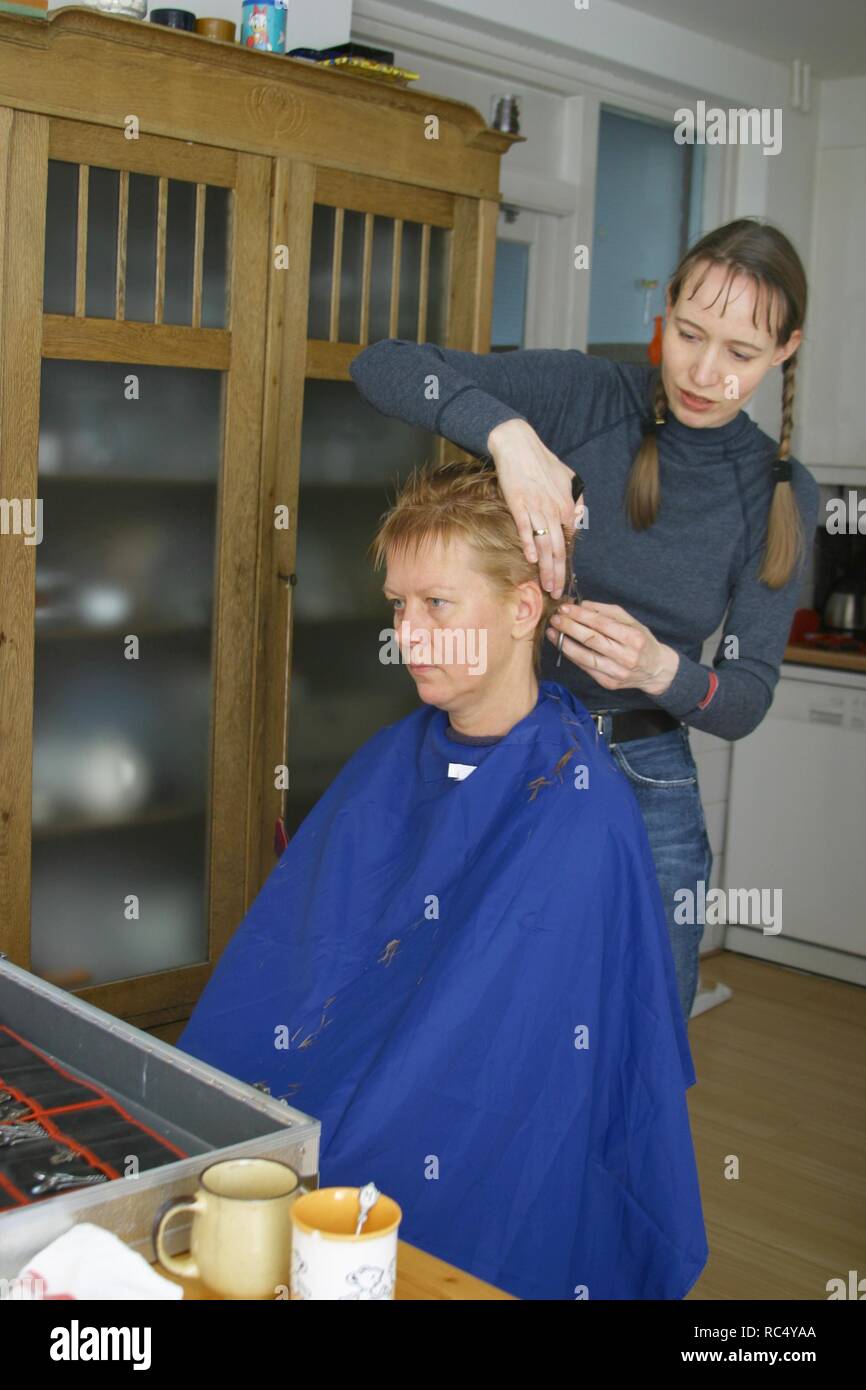 Home hairdresser cutting hair from friend at home Stock Photo