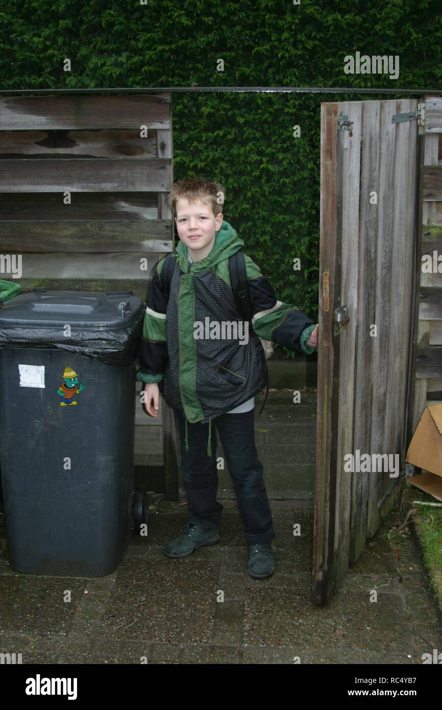 Young boy age 8 arrives from school , at the garden gate. Stock Photo
