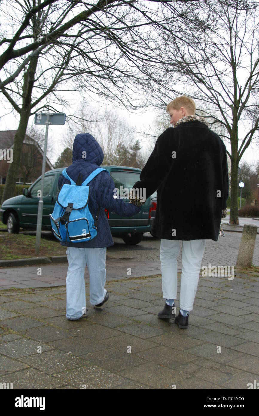 Back view woman picking up a child from school, walking to the car Stock Photo