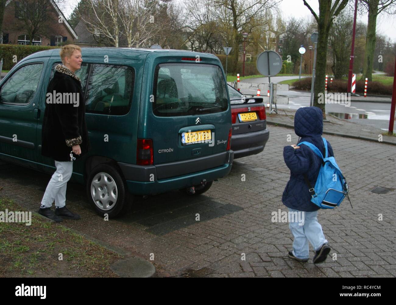 An adult woman picking up a young child from school with the car Stock Photo