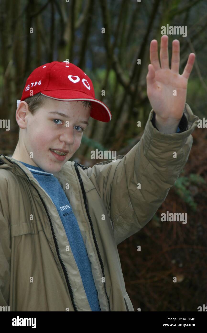 Teenage boy waving with his left hand, outside, and smile, braces Stock Photo