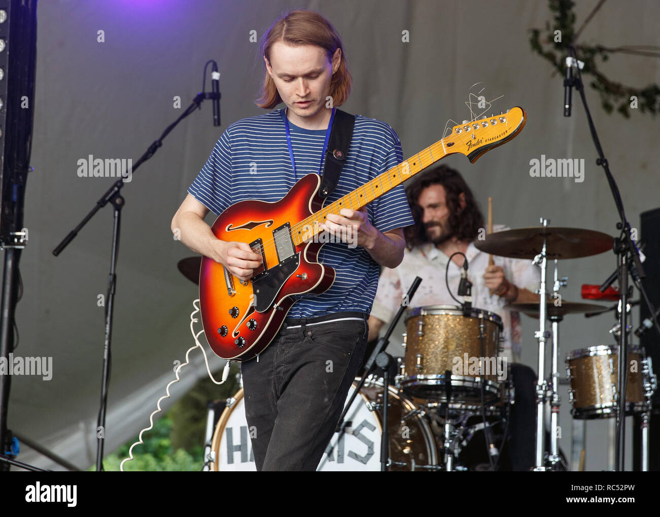 A musician playing a Fender Starcaster guitar live onstage at a music festival. Stock Photo