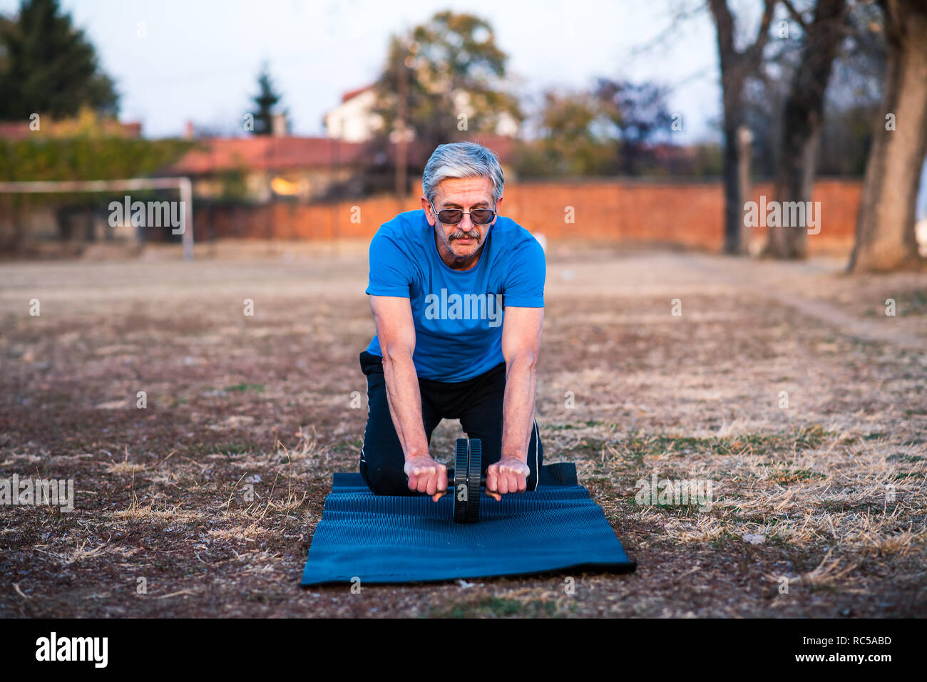 Senior man doing abs exercise with a roller Stock Photo