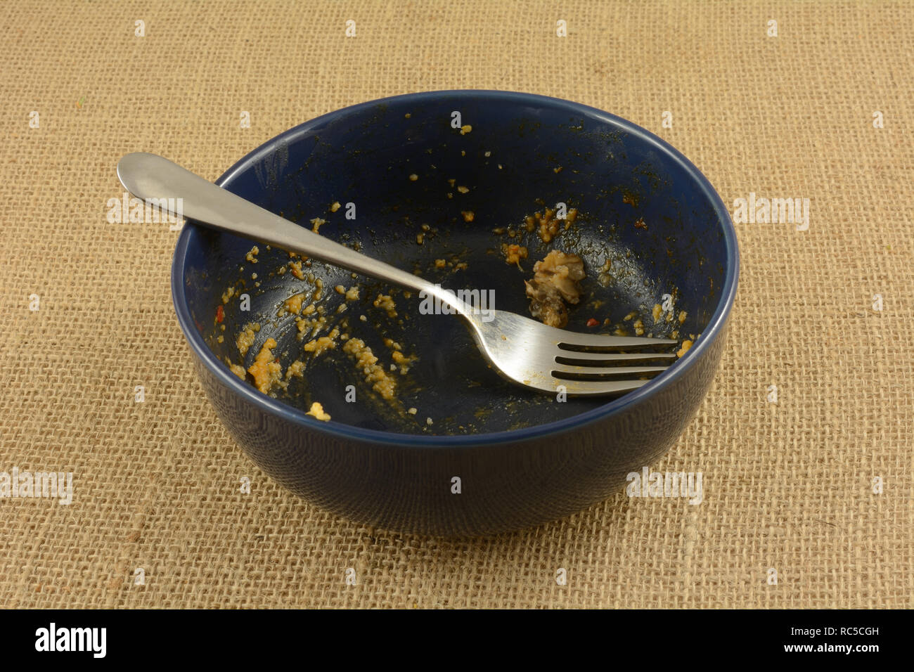 Empty blue bowl with fork with last remnants of cheese grits at end of meal Stock Photo