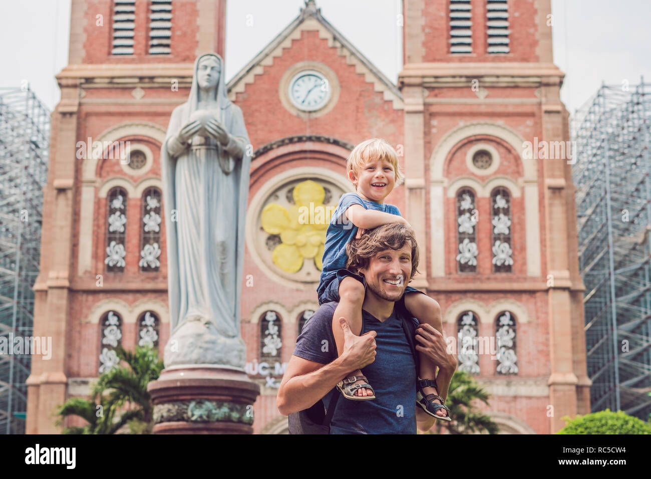 Father and son in the background Notre dame de Saigon Cathedral, build in 1883 in Ho Chi Minh city, Vietnam. Stock Photo
