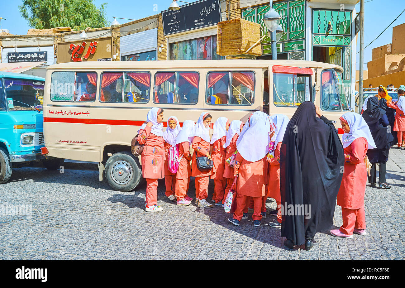 YAZD, IRAN OCTOBER 18, 2017 Pupils in orange Islamic uniform enter their school bus after