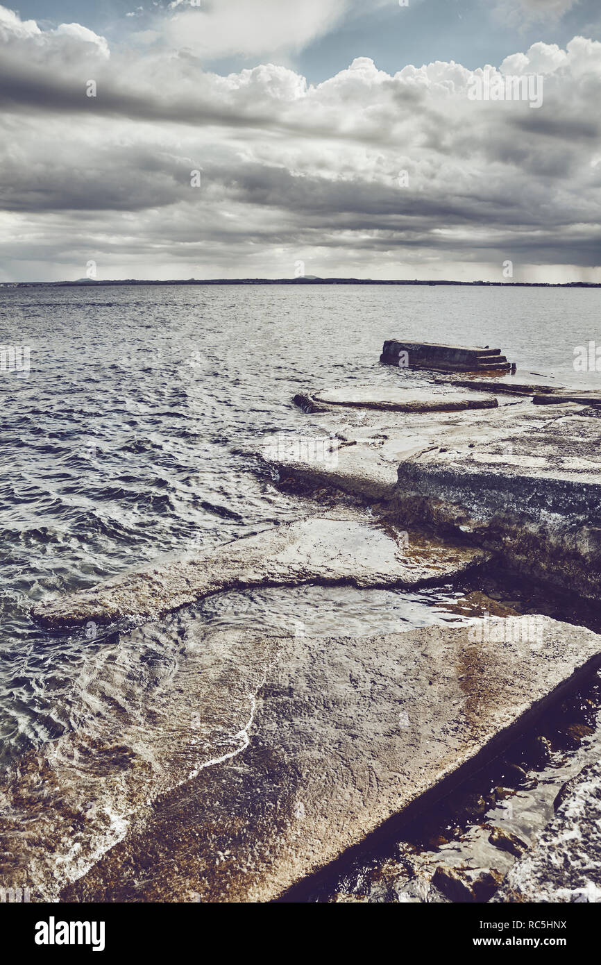 Seascape with a concrete pier, color toned picture. Stock Photo