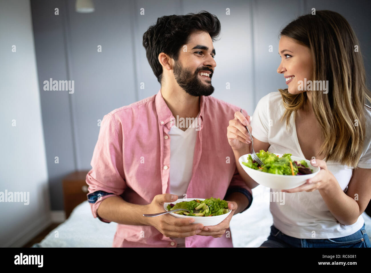 Image of happy young couple eating salad at home Stock Photo