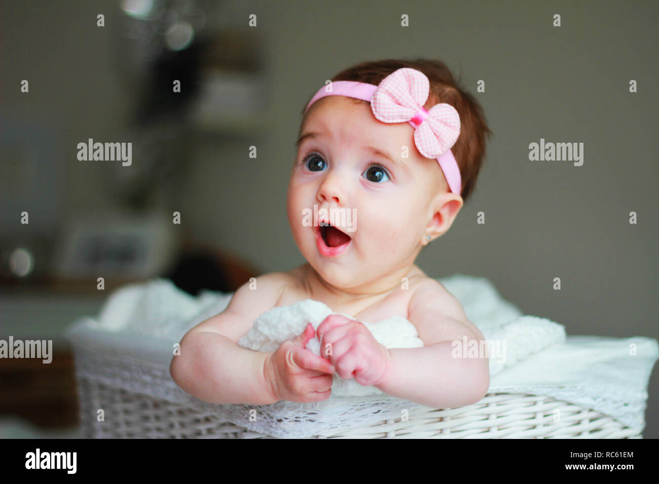 Cute baby girl, with a bow on her hair, with amazement face Stock Photo
