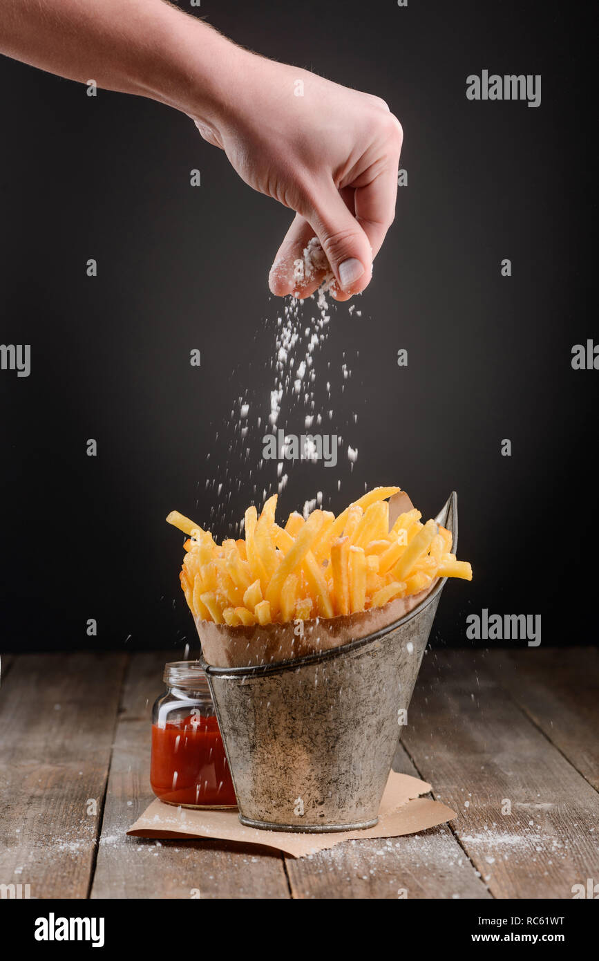 Hand sprinkles salt on fries Stock Photo Alamy