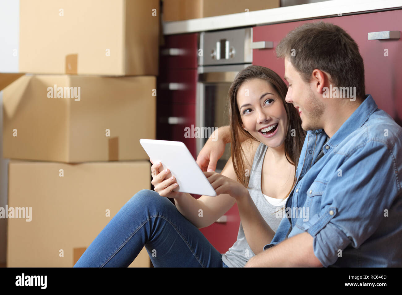 Happy couple moving home checking tablet online content sitting on the ...
