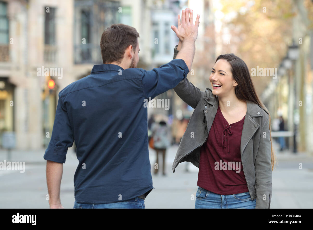 Two happy friends giving high five in the middle of the street Stock ...