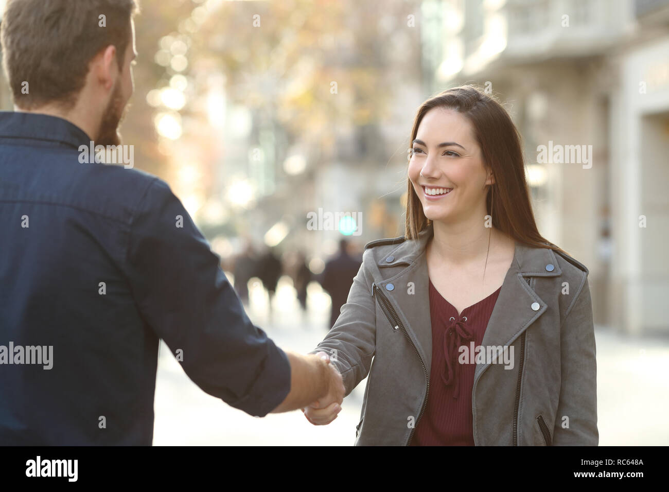 Happy man and woman handshaking closing deal in a city street Stock Photo