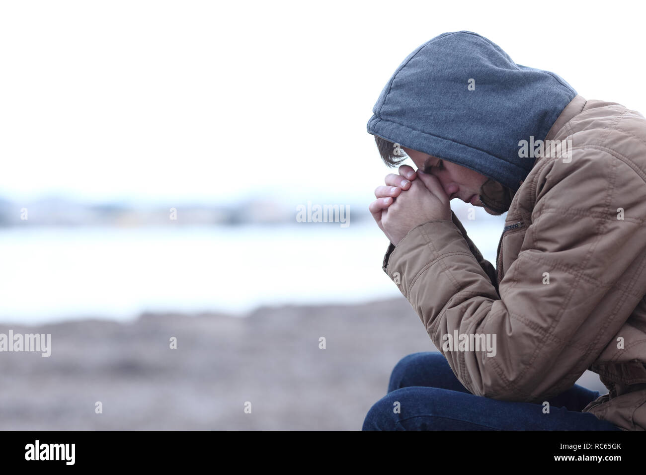 Side view portrait of a sad boy complaining in winter on the beach Stock Photo