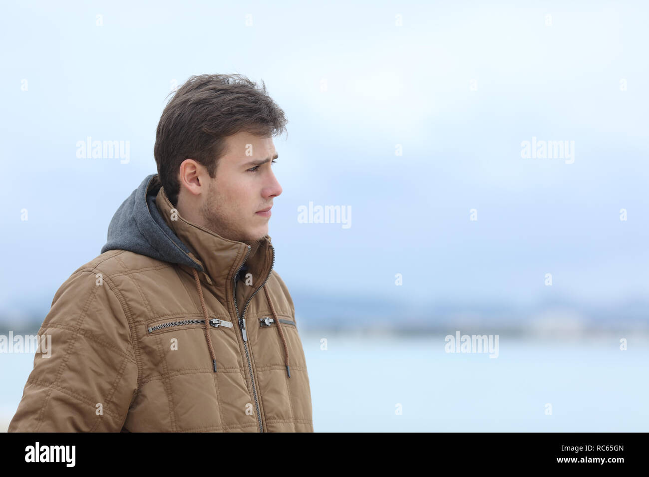 Side view portrait of a sad man looking away on the beach Stock Photo