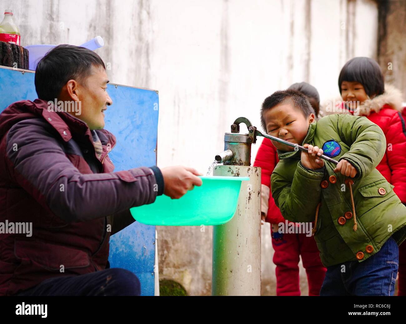 (190114) -- NANCHANG, Jan. 14, 2019 (Xinhua) -- A student helps principal Zhang Zhanliang pump water at Huangni elementary school in Chuntao Town of Yujiang District of Yingtan City, east China's Jiangxi Province, Jan. 3, 2019. Zhang Zhanliang, the principal of Huangni primary school, has been known nationwide recently for taking care of the school's left-behind children, whose parents are migrant workers in towns and cities. For years, there's no canteen at Huangni elementary school. Appointed as principal in 2018, Zhang Zhanliang spent his own money cooking additional meal for these left-beh Stock Photo