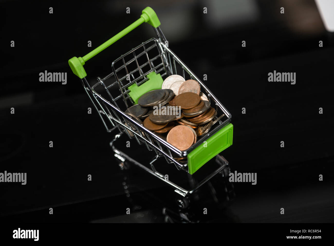 Dummy shopping cart with coins on a black office Desk Stock Photo Alamy