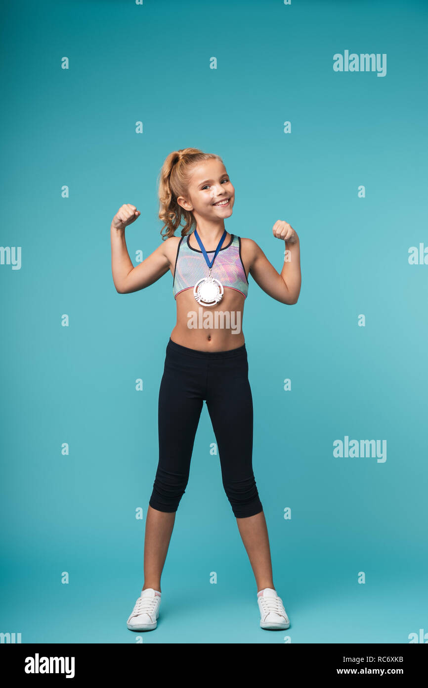 Cheerful little sports girl celebrating the win isolated over blue