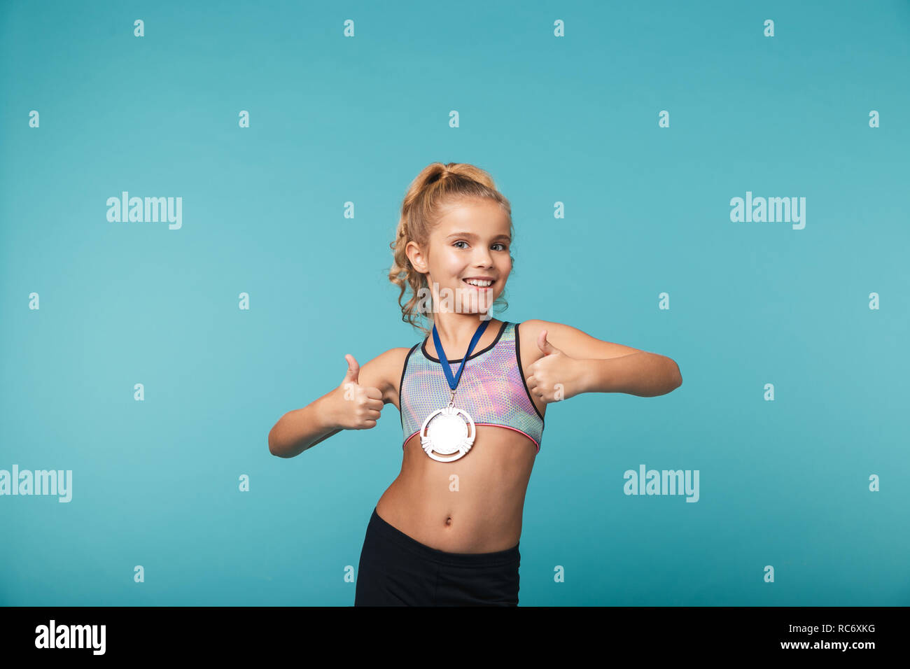 Cheerful little sports girl celebrating the win isolated over blue