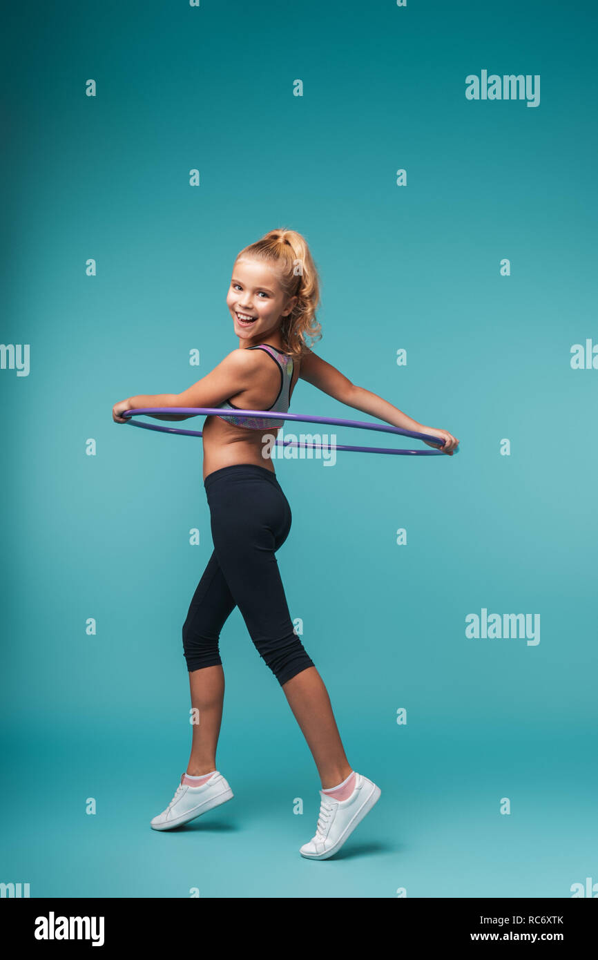 Cheerful little sports girl doing exercises with a hula hoop isolated