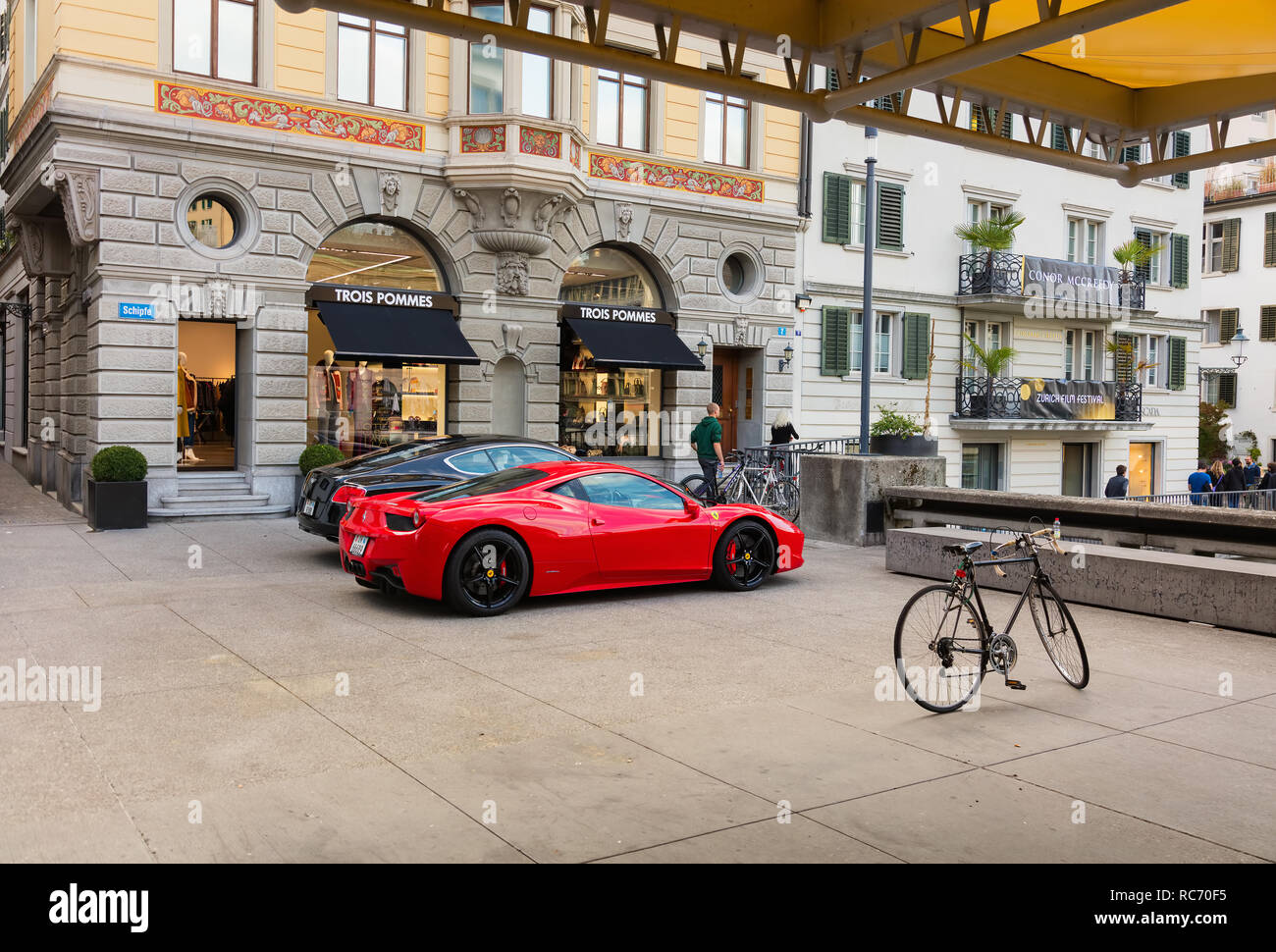 a-red-ferrari-parked-side-by-side-with-a-black-bentley-in-the-old-town-of-the-city-of-zurich-RC70F5.jpg