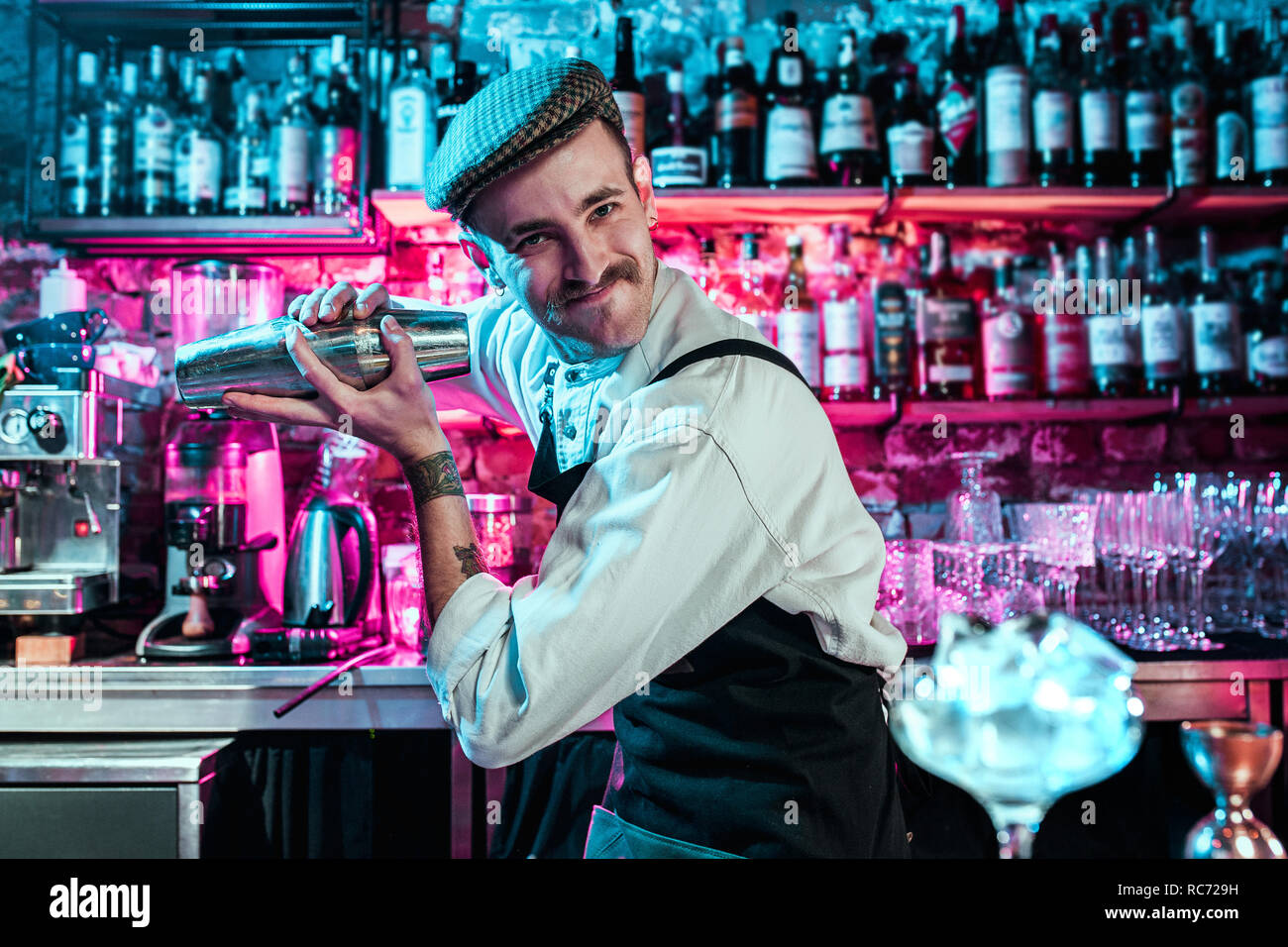 Expert barman is making cocktail at night club or bar. Glass of fiery cocktail on the bar counter against the background of bartenders hands with fire. Barman day concept Stock Photo