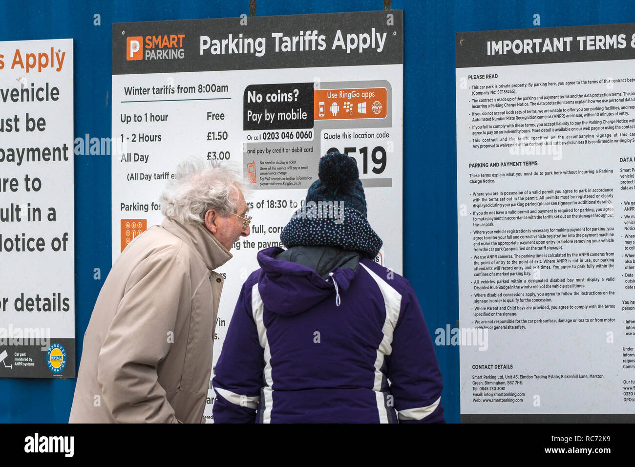 A mature couple looking at car parking rules on signs in Fistral Beach