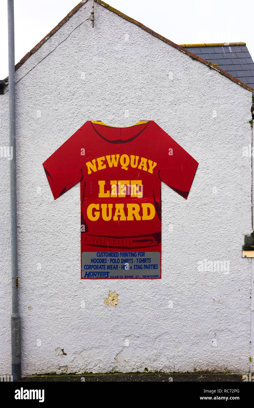 A large sign in the shape of a red T shirt on the side of a building advertising customised printing for clothing. Stock Photo