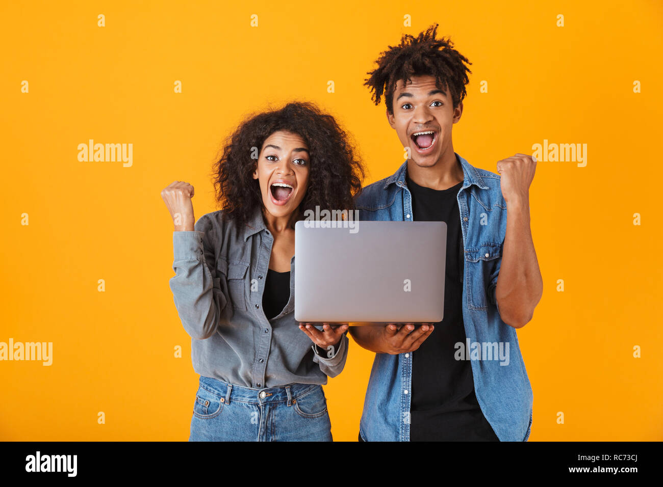 Cheerful young african couple standing isolated over orange background ...
