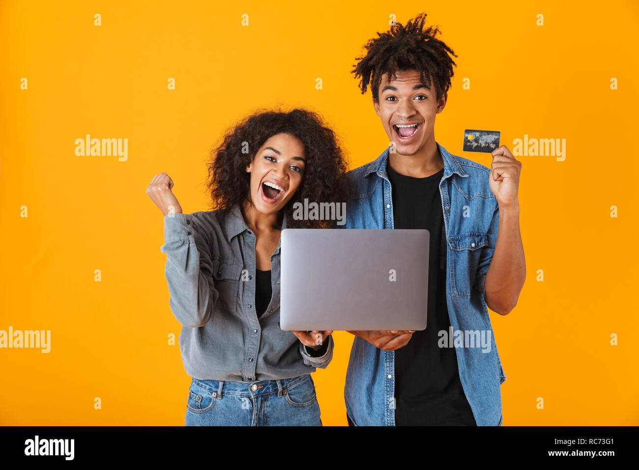 Cheerful young african couple standing isolated over orange background ...