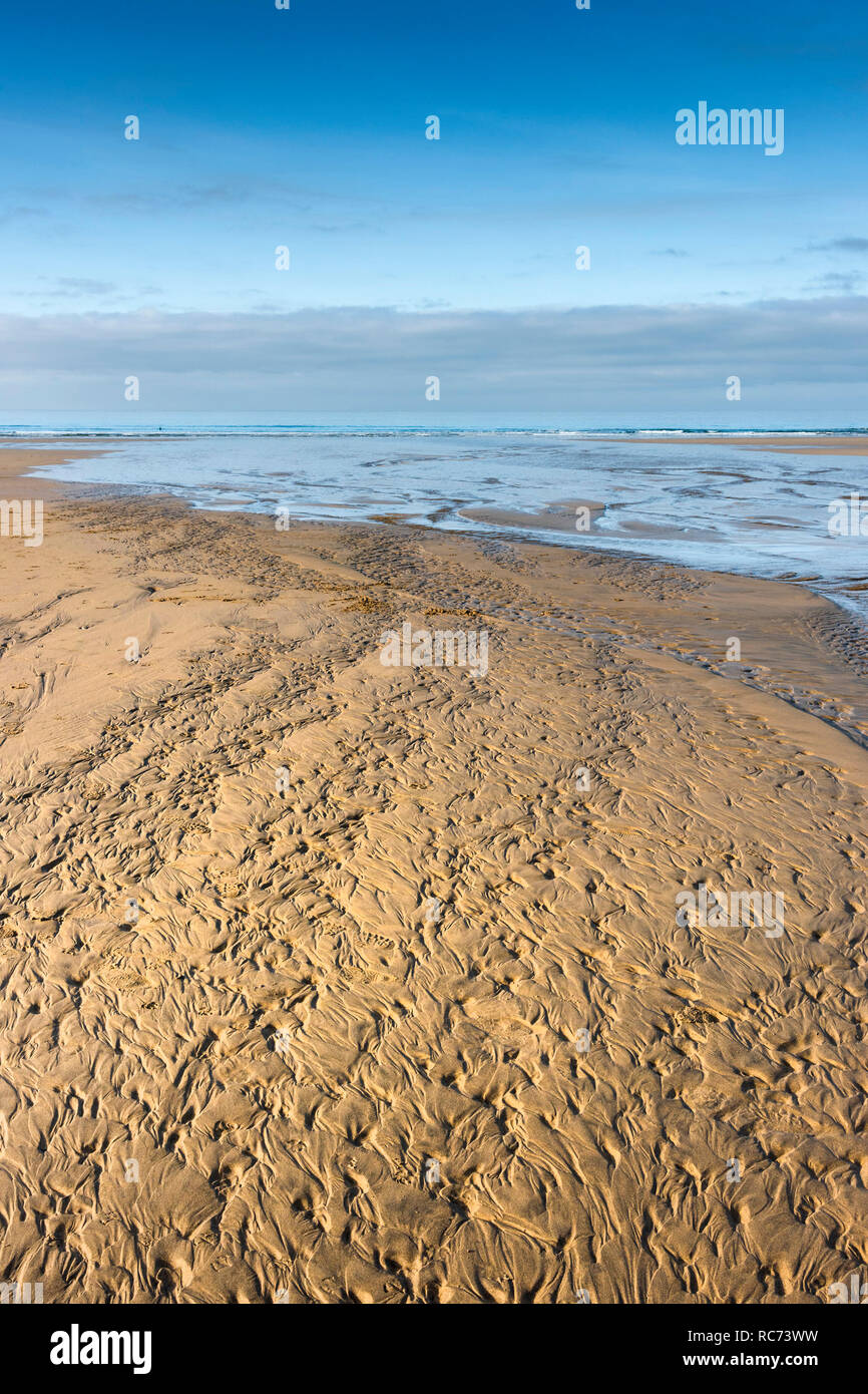 Ripples and patterns left in the sand on a beach at low tide. Stock Photo