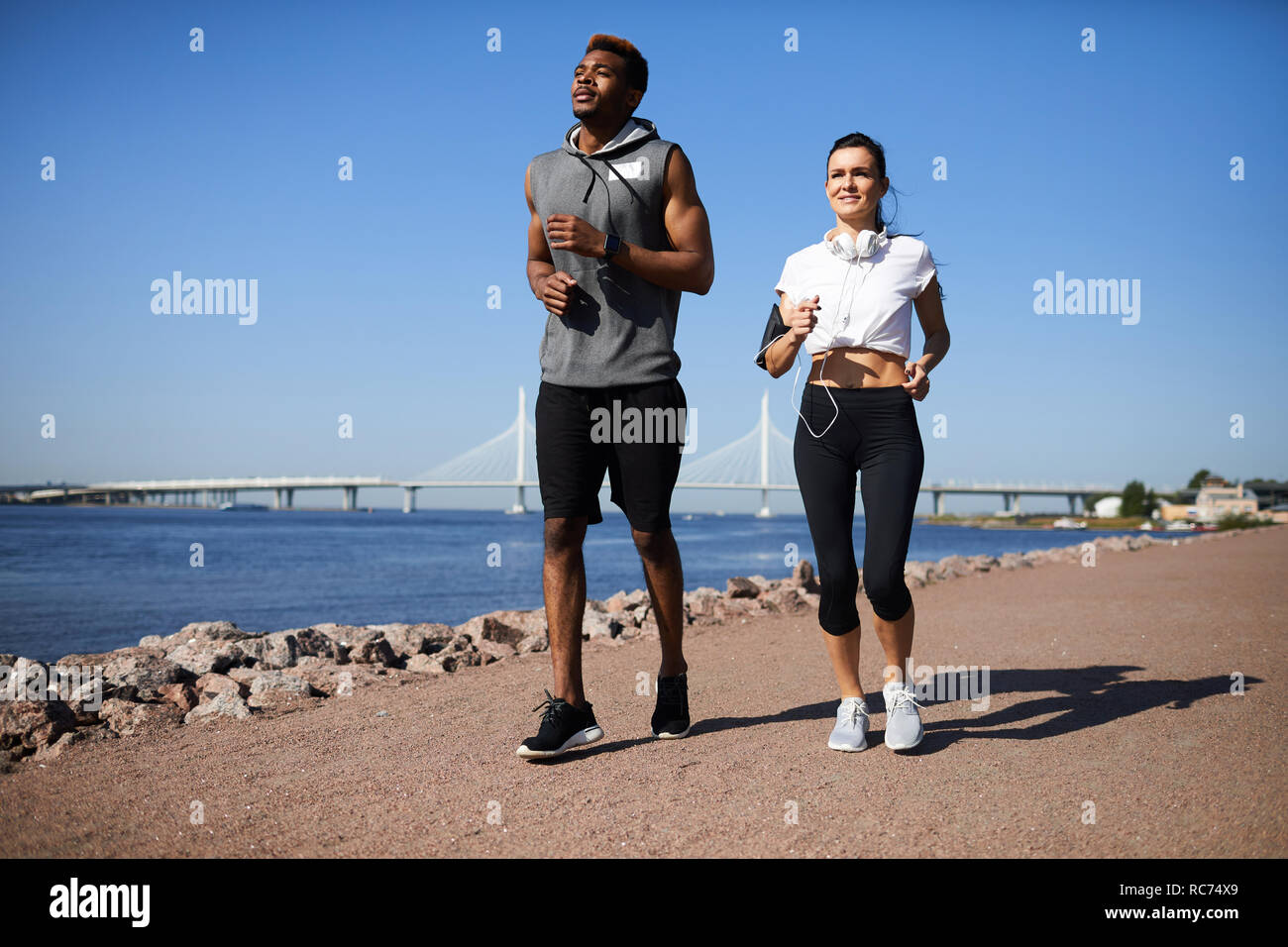 Multi-ethnic couple jogging on city beach Stock Photo