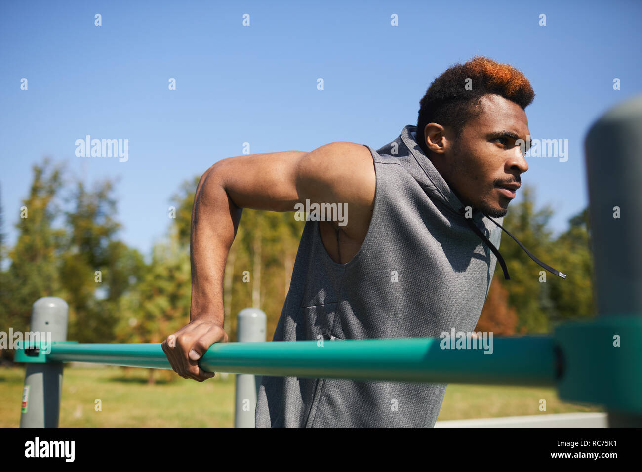 Motivated black man doing dips outdoors Stock Photo