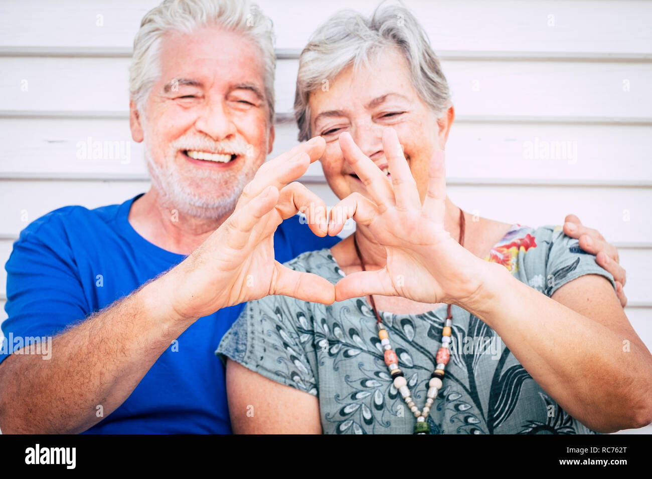 Love and valentine's day concept for cheerful happy couple of senior man and woman caucasian people together doing hearth with hands and smile - happi Stock Photo