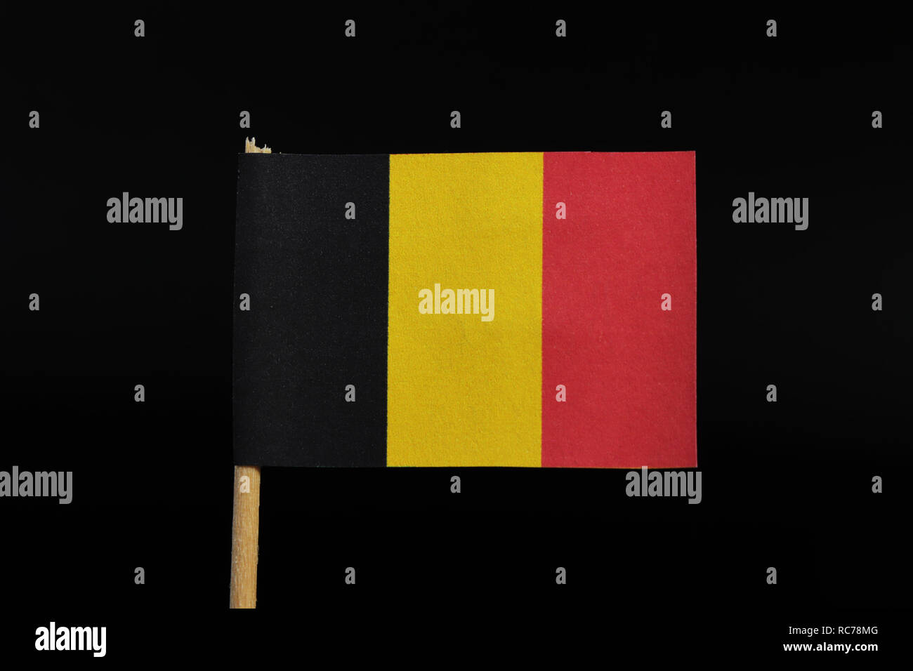 A beautiful, national flag of the kingdom of Belgium on toothpick on black background. A vertical tricolour of black, yellow, and red. Stock Photo