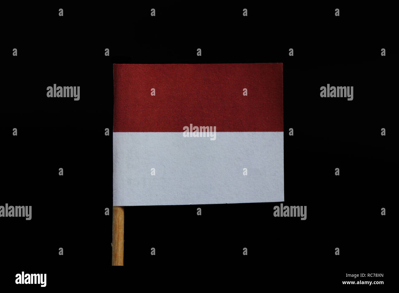 A unique and very simple flag of Monaco on toothpick on black background. A two equal horizontal bands, red and white. Stock Photo