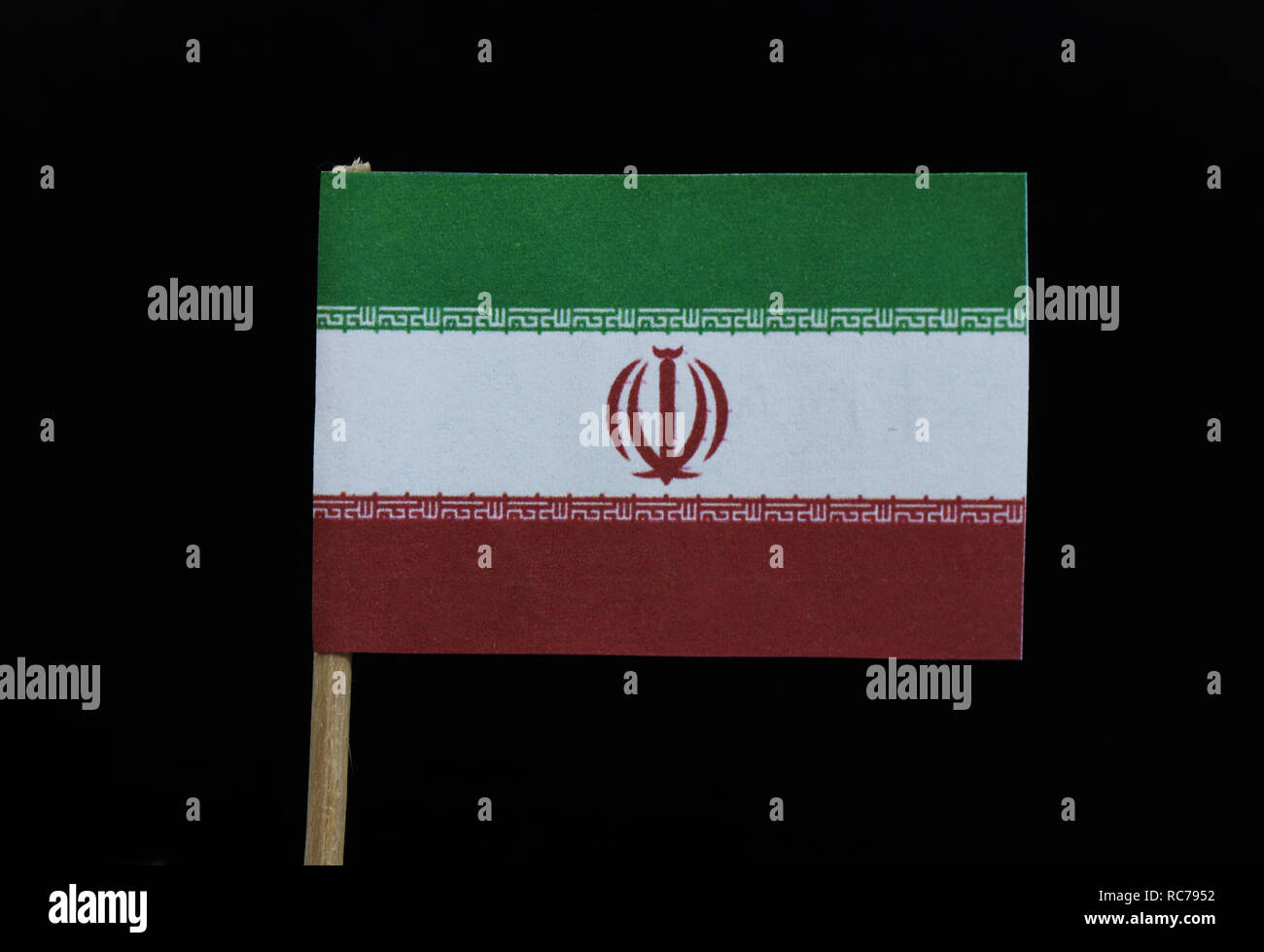 A unique flag of Iran on toothpick on black background. A horizontal tricolor of green, white and red with the national emblem in red centred on the w Stock Photo