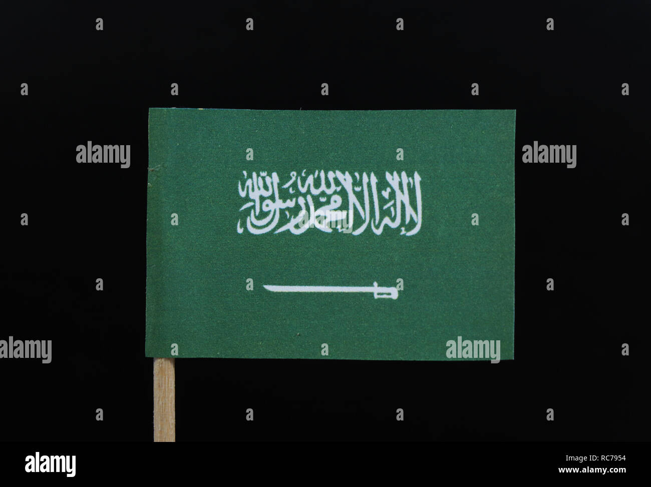 A official and unique flag of the Kingdom of Saudi Arabia on toothpick on black background. A green field with the Shahada or Muslim creed. Stock Photo