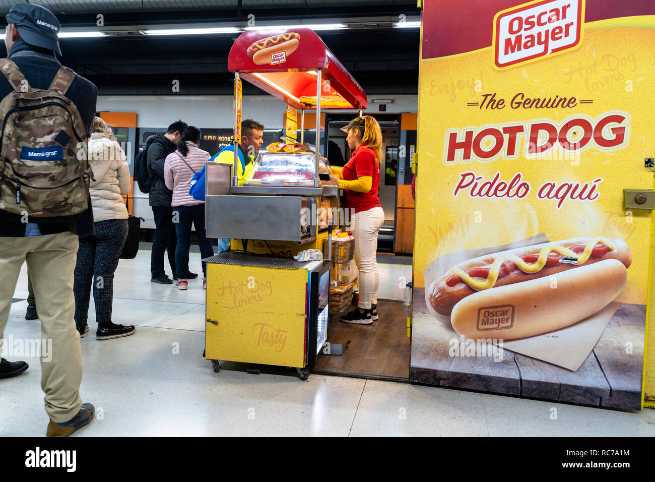 Hot dog vendor serving a hot dog to a traveler in a hot dog stand at