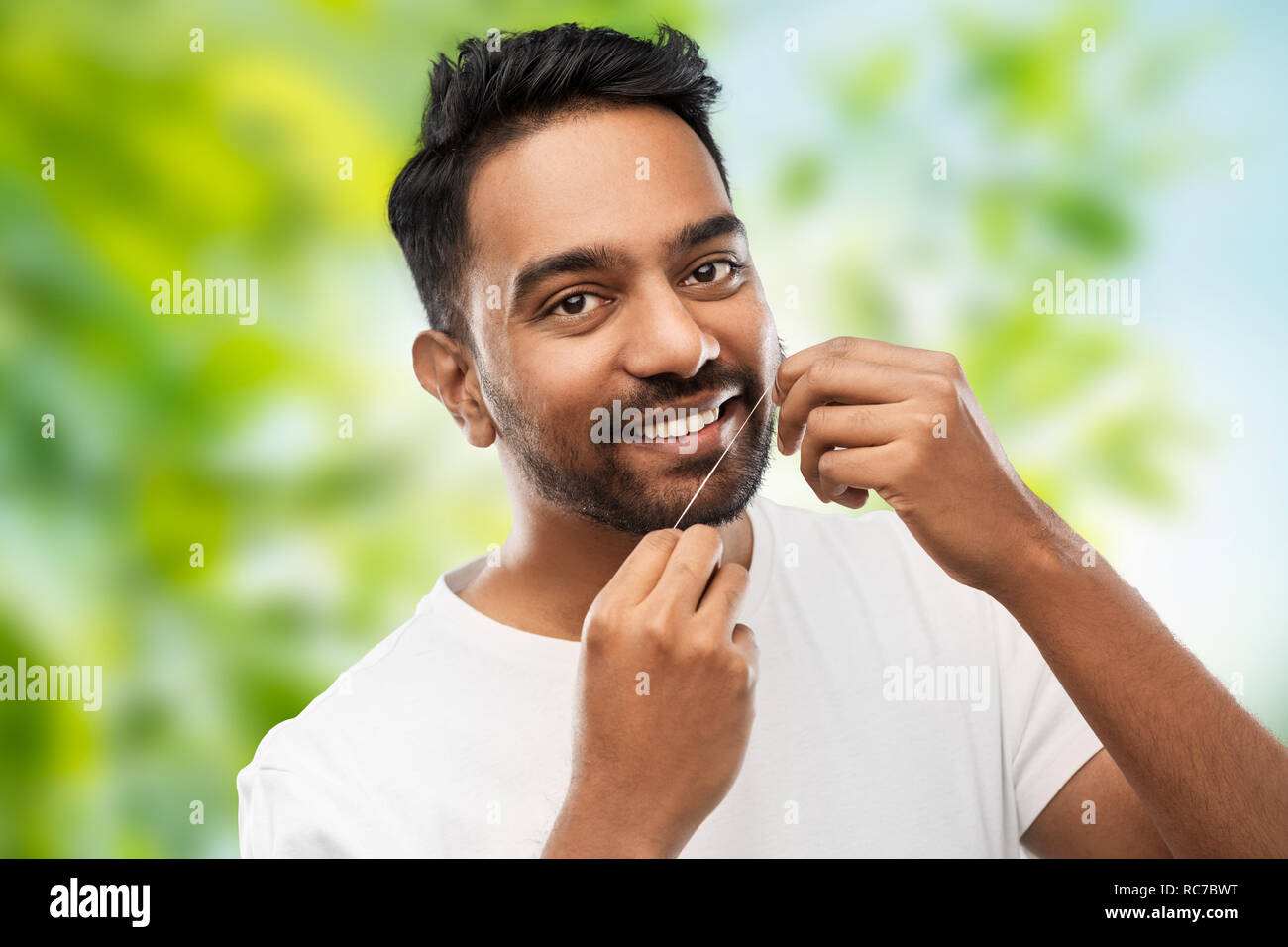 indian man with dental floss cleaning teeth Stock Photo