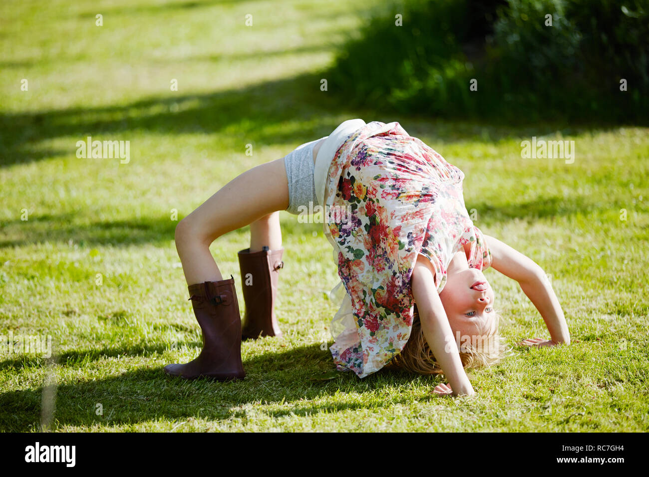 Girl in bridge position in field Stock Photo