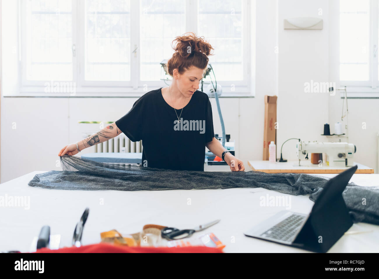 Fashion designer laying out fabric on workbench Stock Photo