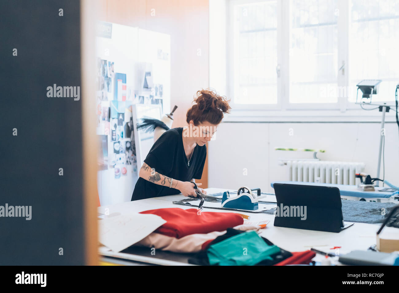 Fashion designer cutting fabric from dressmaker's pattern Stock Photo