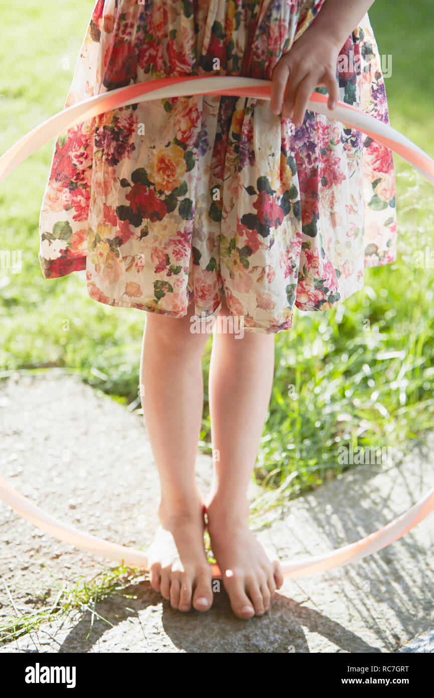 Low-section of girl with plastic hoop in backyard Stock Photo