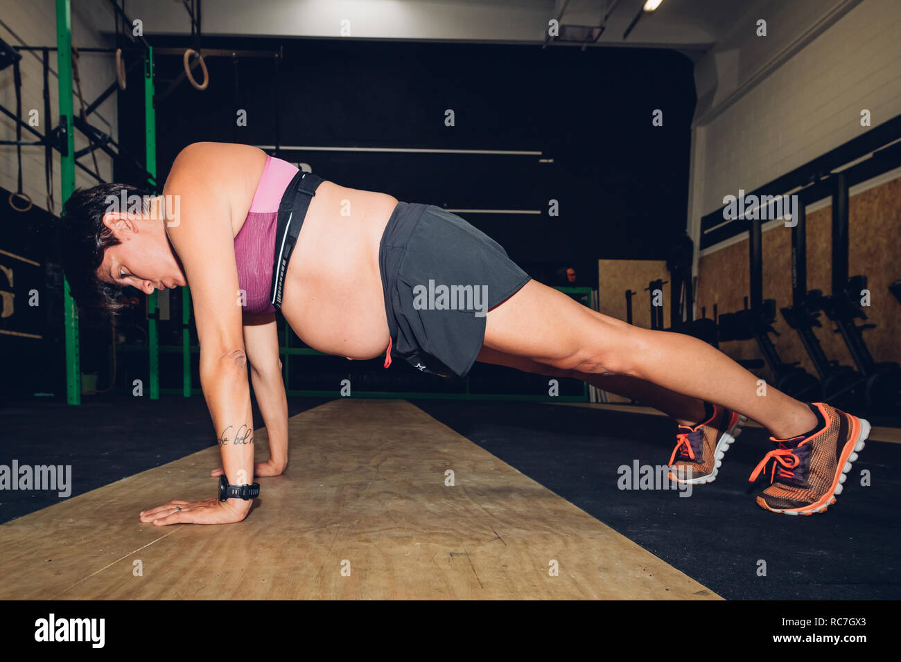 Pregnant woman doing push ups in gym Stock Photo