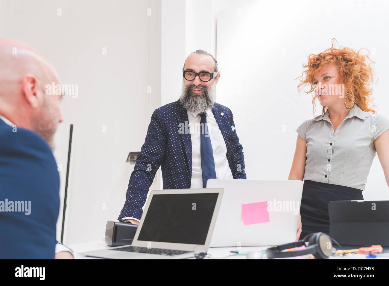 Businesswoman and men chatting over office desk Stock Photo