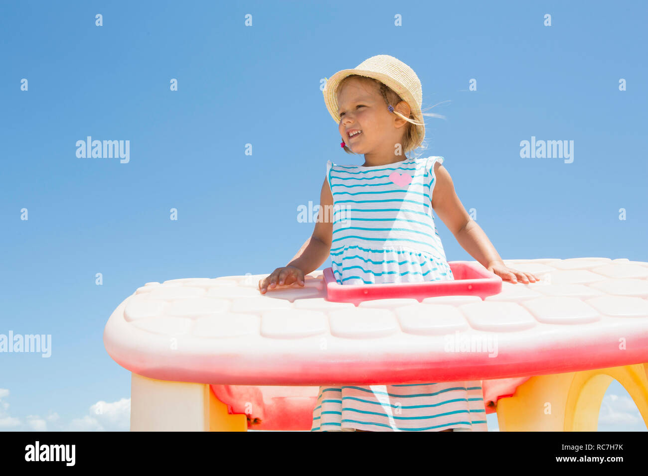 Girl in sun hat looking out from plastic roof on beach,  Castellammare del Golfo, Sicily, Italy Stock Photo