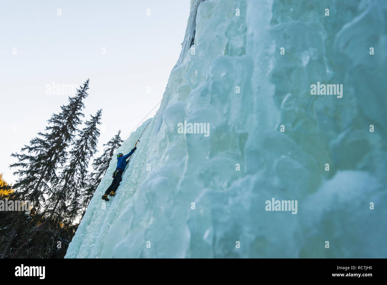 Man climbing up on frozen waterfall Stock Photo