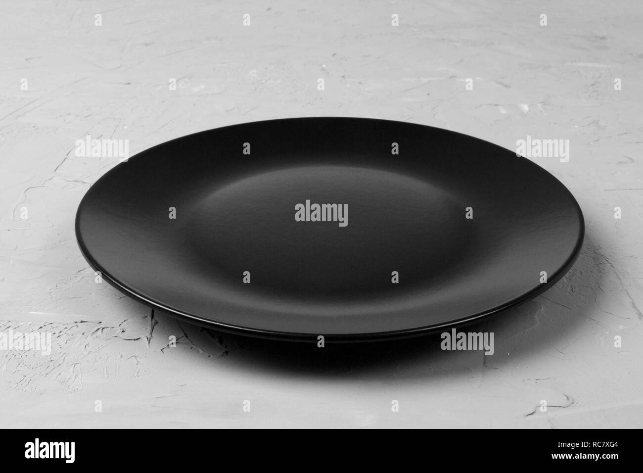 Top view of matte round empty black plate on grey cement background ...